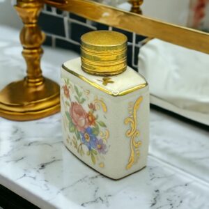 Un flacon en porcelaine blanche fabriquée en France avec un joli décor floral et un bouchon doré 